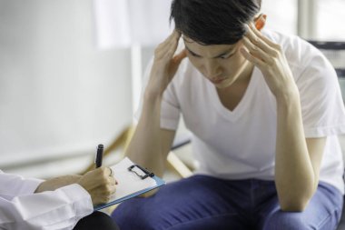 Güzel, genç, Asyalı bir bayan doktor panoya tıbbi bir geçmiş kaydediyor ve erkek hastaya bir şey anlatıyor. Tıbbi ve sağlık hizmetleri kavramları