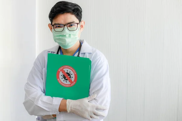 Portrait of Asian male doctor Asian male doctor wearing a uniform with glasses and gloves is standing to hug the file with copy space.