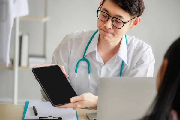 アジアの男性医師は 患者が見るために空白のタブレット画面に表示されます タブレットのモックアップ 現代病院 — ストック写真
