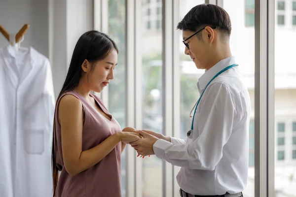 Friendly Asian male doctor\'s hands holding female patient\'s hand for encouragement and empathy. Medical psychology in encouraging and reducing the negative effects of sick people.