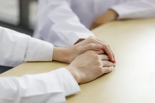 Close up male doctor \'s hands holding female doctors hand for encouragement and empathy. Medical psychology in encouraging and reducing the negative effects of sick people.