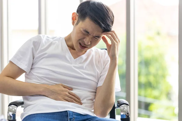 Ung Asiatisk Man Sitter Magen Med Handen Stol Hemmet Grund — Stockfoto