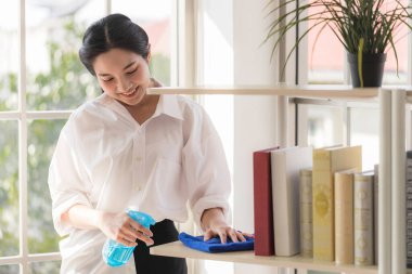 Uzun saçlı Asyalı bir kadın antiseptikle temizlik yapıyor. Gözaltına alınırken evde yapılacak etkinlikler.