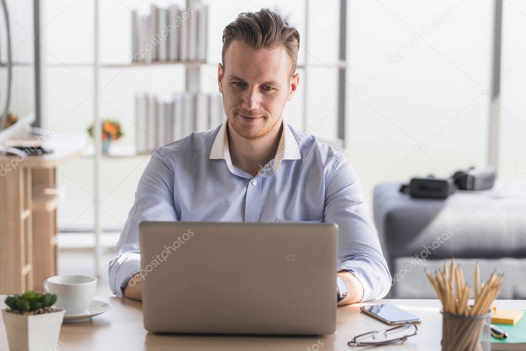 Portrait of young man working from home-office with morning sunshine. happy man communicating in social network and searching information online.