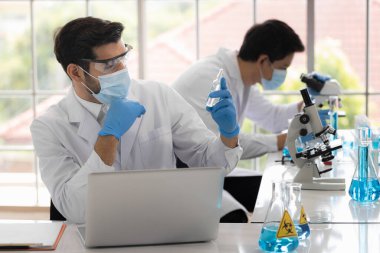 Yaşam bilimi laboratuvarında çalışan sağlık araştırmacıları. Araştırma laboratuarında mikroskop slaytlarını hazırlayan erkek araştırmacı ve denetleyici. Koronavirüs aşısının icadı.