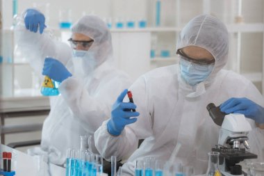 Yaşam bilimi laboratuvarında çalışan sağlık araştırmacıları. Araştırma laboratuarında mikroskop slaytlarını hazırlayan erkek araştırmacı ve denetleyici. Koronavirüs aşısının icadı.