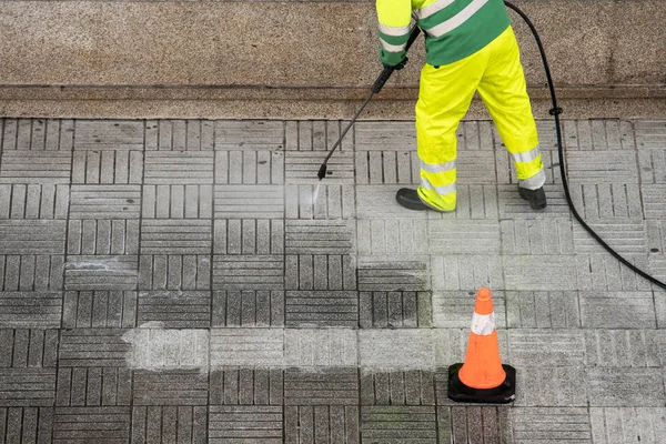 Arbeiter säubert Gehweg mit Hochdruckwasserstrahl — Stockfoto