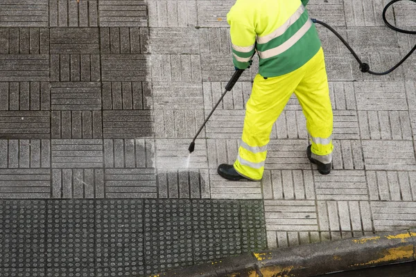 Arbeiter säubert Gehweg mit Hochdruckwasserstrahl — Stockfoto
