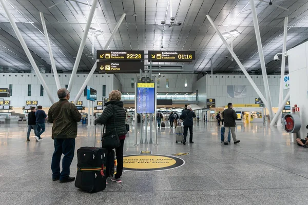 Santiago de Compostela, Hiszpania. 19 2019 kwietnia: Lotnisko Santiago de Compostela. Wnętrze terminalu pasażerskiego. Para patrząc na tablicy informacyjnej — Zdjęcie stockowe