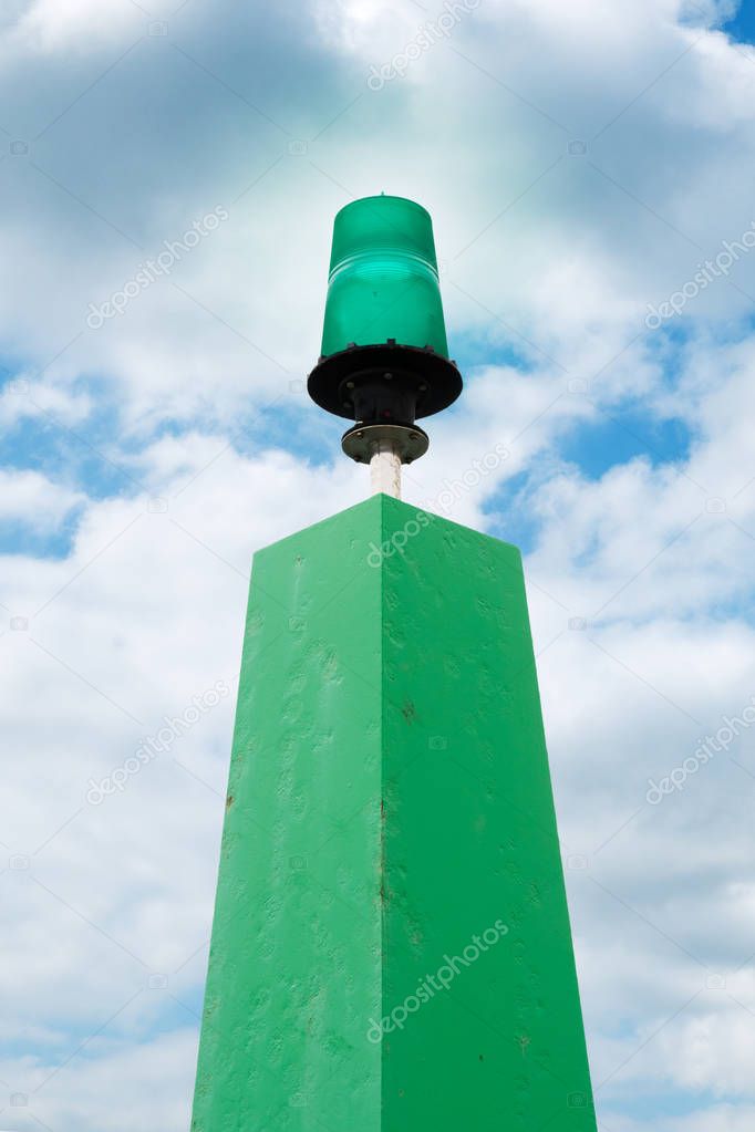 Harbor pier light. Marine green light with cloudy sky background