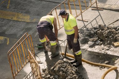 İşçiler yolda bozuk bir su borusunu tamir ediyorlar.