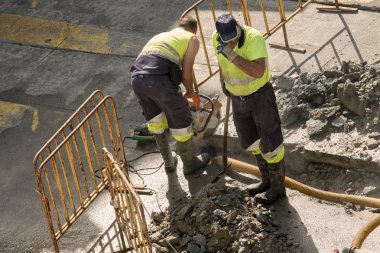 İşçiler yolda bozuk bir su borusunu tamir ediyorlar.