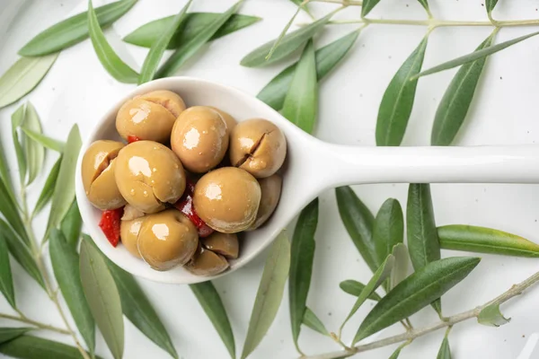 Spiced olives on white spoon — Stock Photo, Image