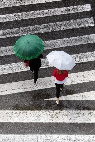 ฉากของผู้หญิงสองคนที่มีร่มแฟชั่นข้ามทางเท้า ท็อปวิว — ภาพถ่ายสต็อก