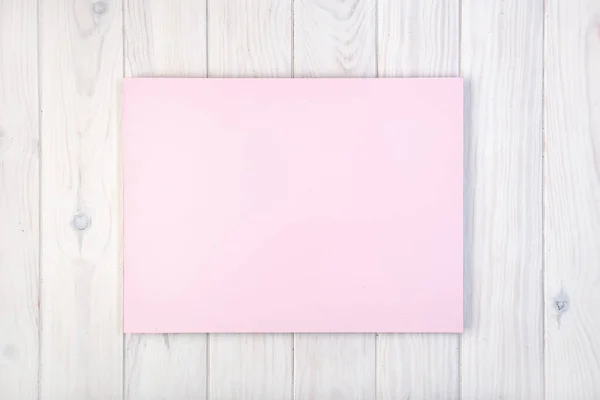 Composición plana con tablero rosa sobre mesa de madera blanca — Foto de Stock