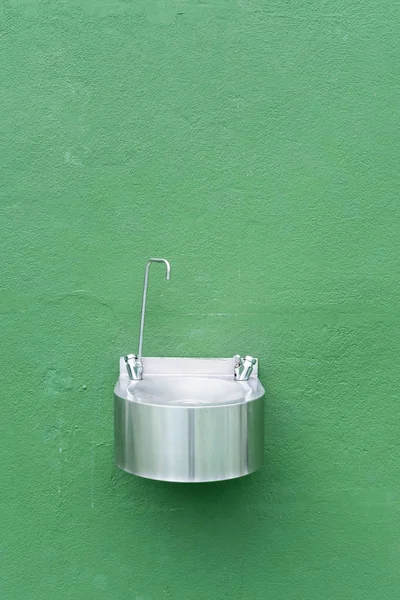 Zelená stěna s kovovou fontánou na tenisovém kurtu — Stock fotografie