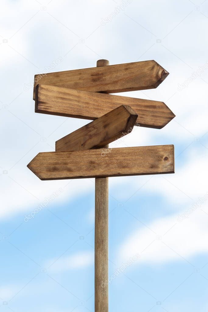 Wooden sign post isolated on blue sky with white clouds. Direction concept. Mock up, template