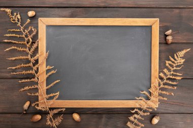 Kırsal ahşap masa üzerinde sonbahar dekorasyonlu boş bir karatahta. Şablon oluşturun. Sonbahar Arkaplanı. Üst görünüm