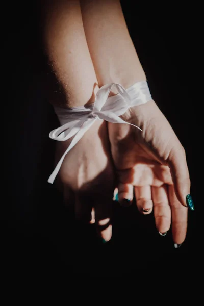 tied hands with ribbon isolated on black background highlighted with light