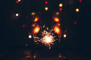 köpüklü Bengal maytap sopa ışıklar bokeh ve şarap gözlük siyah bir zemin üzerine alevler içinde. Noel Tema yeni yıl arka plan. tatil kartı