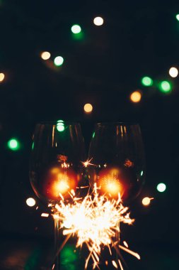 köpüklü Bengal maytap sopa ışıklar bokeh ve şarap gözlük siyah bir zemin üzerine alevler içinde. Noel Tema yeni yıl arka plan. tatil kartı