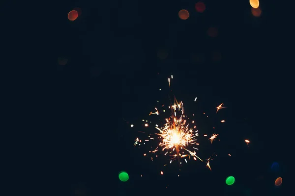 Sparkling Bengala sparklers fica em chamas sobre um fundo preto com luzes bokeh. Natal tema fundo do ano novo. cartão de férias — Fotografia de Stock