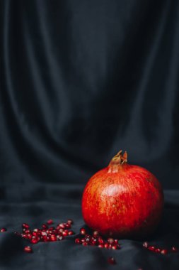 Olgun bütün kırmızı nar nar taneleri, bir siyah kumaş arka plan üzerinde yakın çekim, Natürmort, oryantal meyve izole