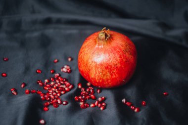 Olgun bütün kırmızı nar nar taneleri, bir siyah kumaş arka plan üzerinde yakın çekim, Natürmort, oryantal meyve izole
