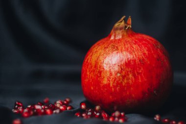 Olgun bütün kırmızı nar nar taneleri, bir siyah kumaş arka plan üzerinde yakın çekim, Natürmort, oryantal meyve izole
