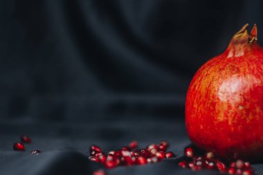 Olgun bütün kırmızı nar nar taneleri, bir siyah kumaş arka plan üzerinde yakın çekim, Natürmort, oryantal meyve izole