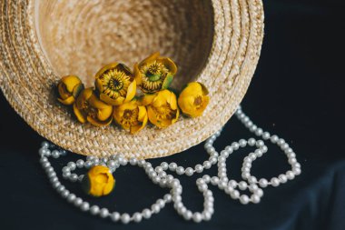 yeşil yaprak ile sarı nilüfer çiçek buketi. taze sökük. Bir hasır şapka. kumaş siyah arka plan üzerine kapatın. Sarı nilüfer. ufuk bitki, kırmızı veri kitap. çiçek kompozisyon düz yatıyordu