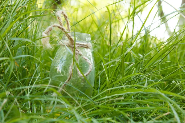 En flaska hemmagjord saft saft ligger på gräset utomhus. Picknick på naturen i parken mot bakgrund av träd med strålande solsken. hälsosam mat, diet — Stockfoto