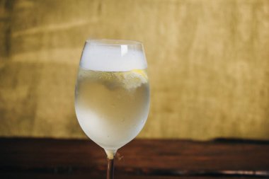 Rustik ahşap kahverengi arka planda buz ve limon içeren bir bardak ev yapımı limonata. dinlenme, tatil, parti. Kristal cam çekim. Kopyalama alanı