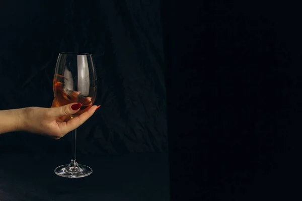 Обрезанная женская рука с бокалом белого вина на черном фоне. отдых, отдых, вечеринка. изолированные алкогольные напитки крупным планом . — стоковое фото