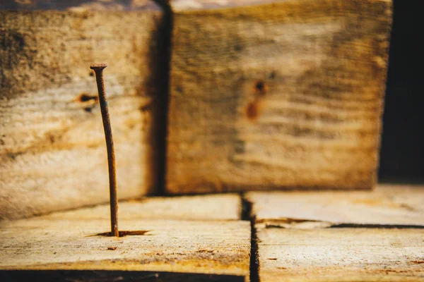Antiguo clavo de curva oxidada larga clavado en una barra de madera sobre un fondo de madera rústico de cerca. macro — Foto de Stock