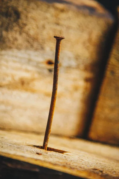 Antiguo clavo de curva oxidada larga clavado en una barra de madera sobre un fondo de madera rústico de cerca. macro — Foto de Stock