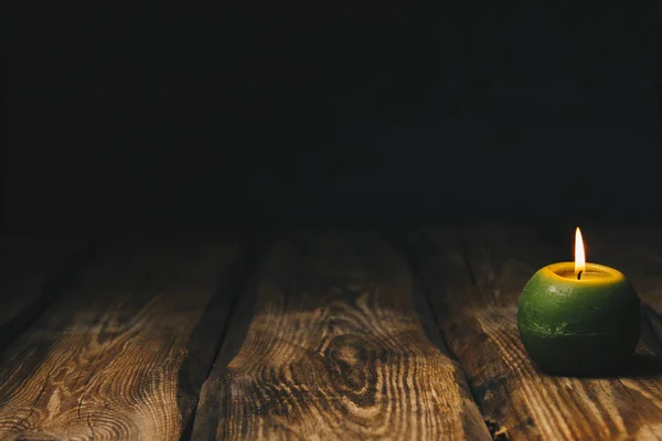Vela en forma de bola verde solitario quema en una mesa de madera rústica de cerca —  Fotos de Stock