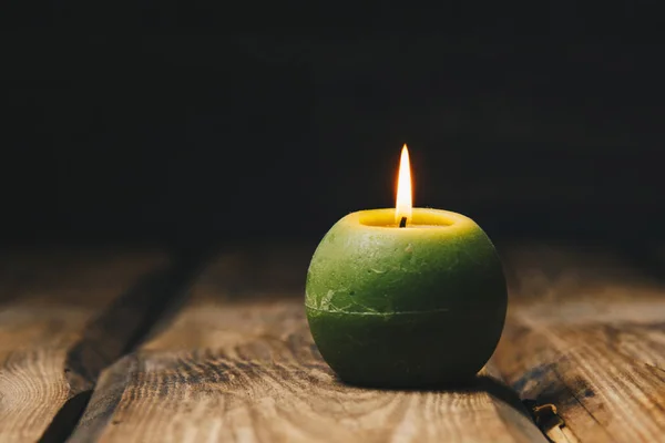 Bougie verte solitaire en forme de bougie brûle sur une table en bois rustique close-up — Photo