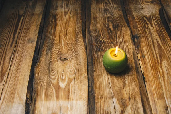 Vela en forma de bola verde solitario quema en una mesa de madera rústica de cerca —  Fotos de Stock