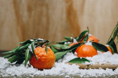 Bulanık bir arka plan üzerinde ahşap bir mutfak masasında yaprakları ile Mandalina narenciye. sağlıklı gıda. çiğ gıda Yapay beyaz kar. Yeni yıl. Noel
