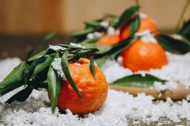 Bulanık bir arka plan üzerinde ahşap bir mutfak masasında yaprakları ile Mandalina narenciye. sağlıklı gıda. çiğ gıda Yapay beyaz kar. Yeni yıl. Noel