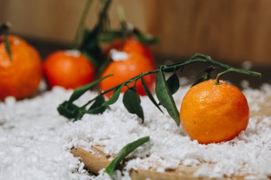 Bulanık bir arka plan üzerinde ahşap bir mutfak masasında yaprakları ile Mandalina narenciye. sağlıklı gıda. çiğ gıda Yapay beyaz kar. Yeni yıl. Noel