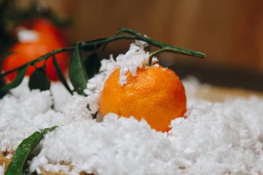 Bulanık bir arka plan üzerinde ahşap bir mutfak masasında yaprakları ile Mandalina narenciye. sağlıklı gıda. çiğ gıda Yapay beyaz kar. Yeni yıl. Noel