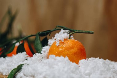 Bulanık bir arka plan üzerinde ahşap bir mutfak masasında yaprakları ile Mandalina narenciye. sağlıklı gıda. çiğ gıda Yapay beyaz kar. Yeni yıl. Noel