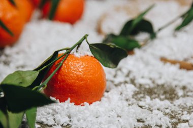 Bulanık bir arka plan üzerinde ahşap bir mutfak masasında yaprakları ile Mandalina narenciye. sağlıklı gıda. çiğ gıda Yapay beyaz kar. Yeni yıl. Noel