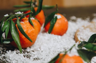 Bulanık bir arka plan üzerinde ahşap bir mutfak masasında yaprakları ile Mandalina narenciye. sağlıklı gıda. çiğ gıda Yapay beyaz kar. Yeni yıl. Noel