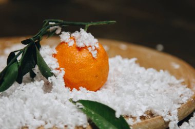 Bulanık bir arka plan üzerinde ahşap bir mutfak masasında yaprakları ile Mandalina narenciye. sağlıklı gıda. çiğ gıda Yapay beyaz kar. Yeni yıl. Noel