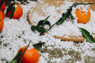 Bulanık bir arka plan üzerinde ahşap bir mutfak masasında yaprakları ile Mandalina narenciye. sağlıklı gıda. çiğ gıda Yapay beyaz kar. Yeni yıl. Noel