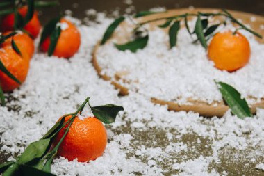 Bulanık bir arka plan üzerinde ahşap bir mutfak masasında yaprakları ile Mandalina narenciye. sağlıklı gıda. çiğ gıda Yapay beyaz kar. Yeni yıl. Noel