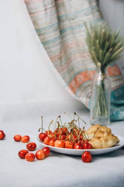 healthy light breakfast. sweet cherry with croissants on a plate. bouquet in a vase with spikelets of wheat. Ingredients for yogurt. proper nutrition for a slim figure. raw foods vegetarianism. diet